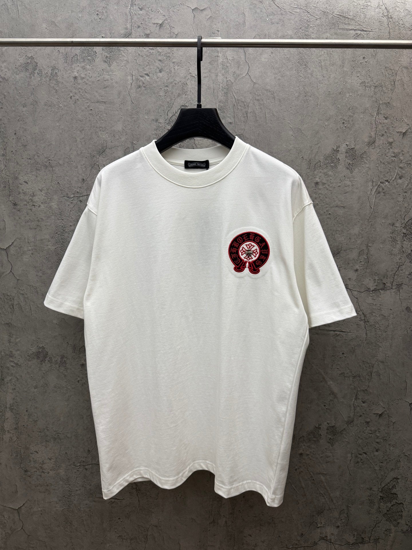 White crew-neck T-shirt with small red-and-black chest logo graphic.