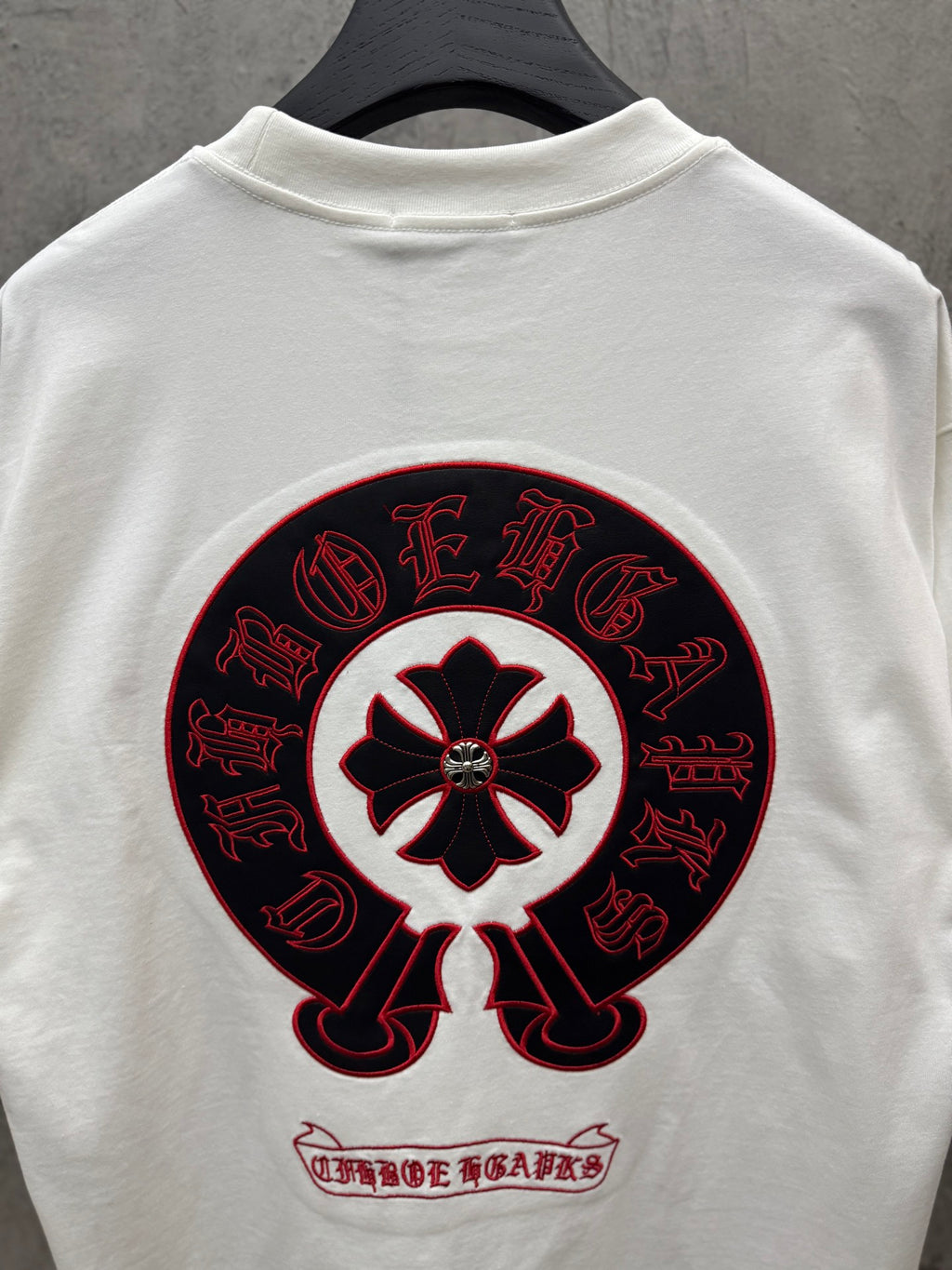 White T-shirt back view with large circular red-and-black graphic and small text.