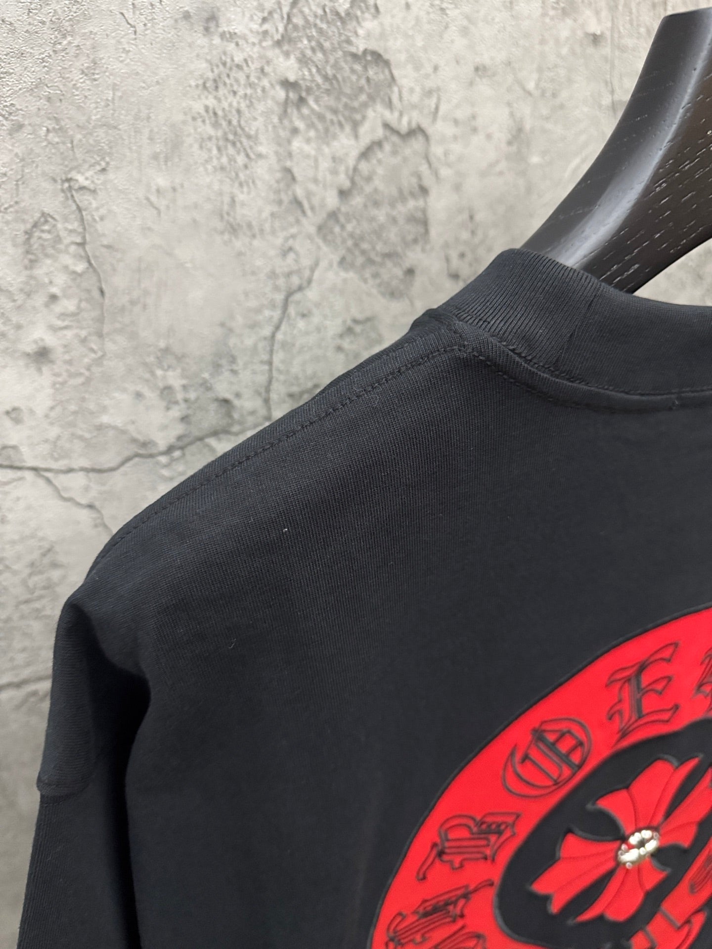 Black short-sleeve T-shirt side view with red logo on sleeve/hem area