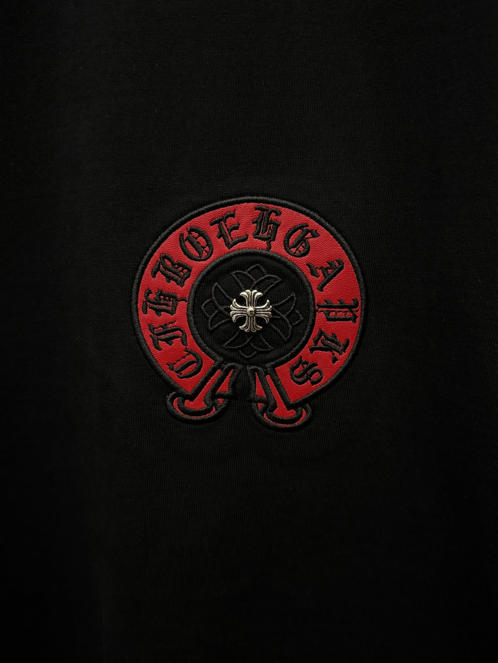 Close-up of black T-shirt chest emblem with red ring and dark center design