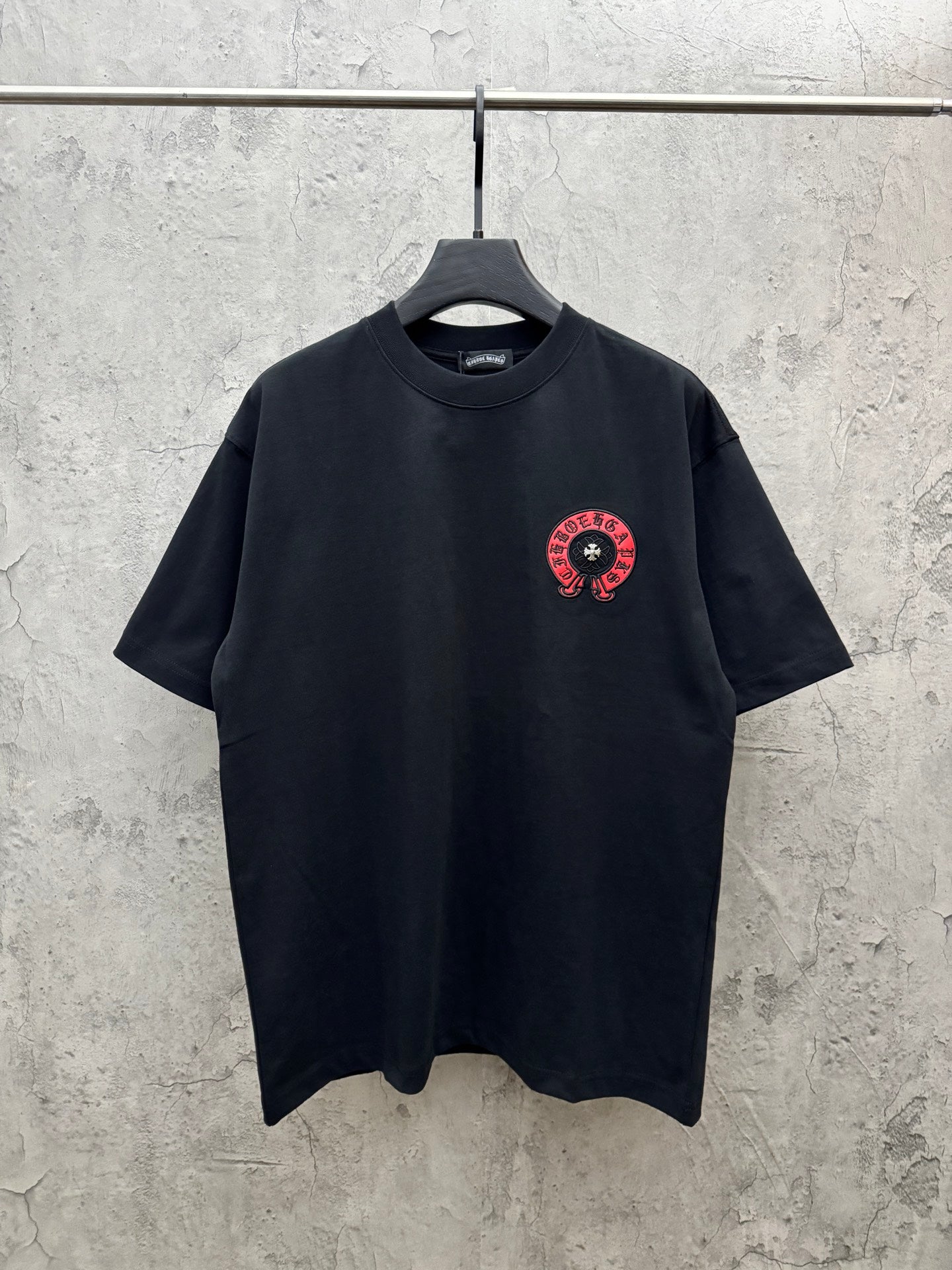 Black short-sleeve T-shirt with small red-and-black chest emblem