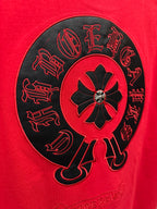 Close-up of black embroidered circular emblem on red T-shirt back.
