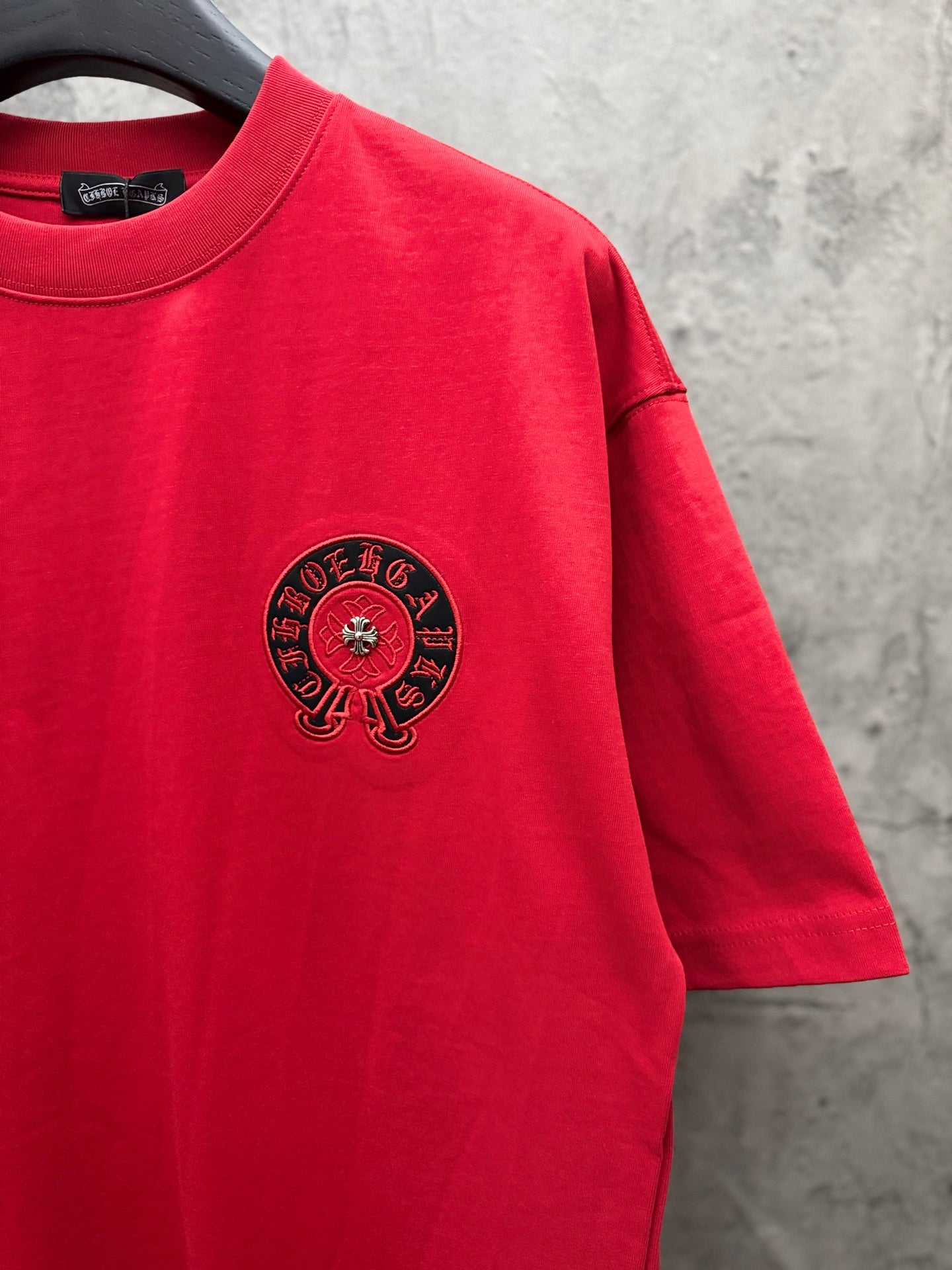 Red T-shirt with black circular chest logo and short sleeves