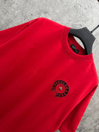 Red T-shirt neckline close-up with small black circular chest emblem