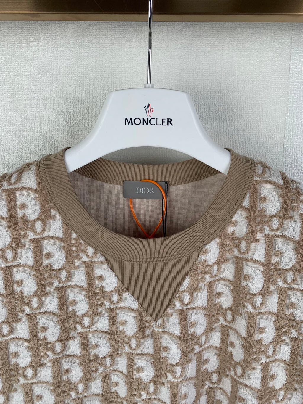 Tan short-sleeve top with crew-to-V neckline ribbed trim and logo pattern