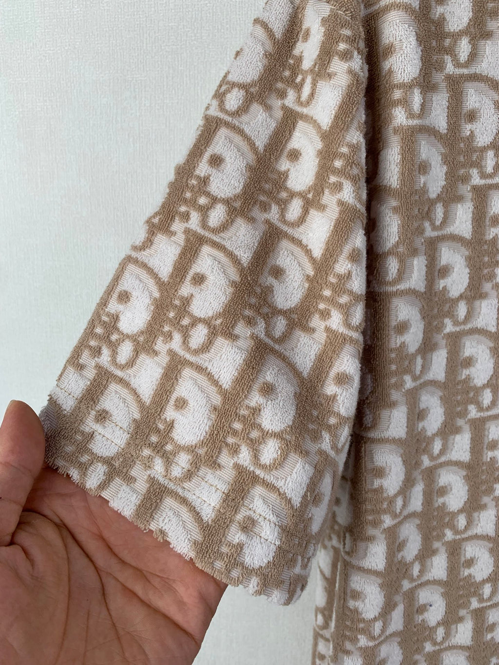 Sleeve detail of tan short-sleeve top with repeating logo pattern