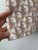 Close-up of tan logo-pattern fabric with textured embroidery effect