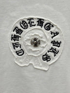 Embroidered round logo patch on white T-shirt with small cross detail