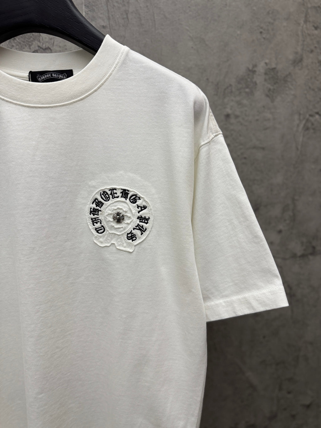 White short-sleeve T-shirt with small circular embroidered logo on chest