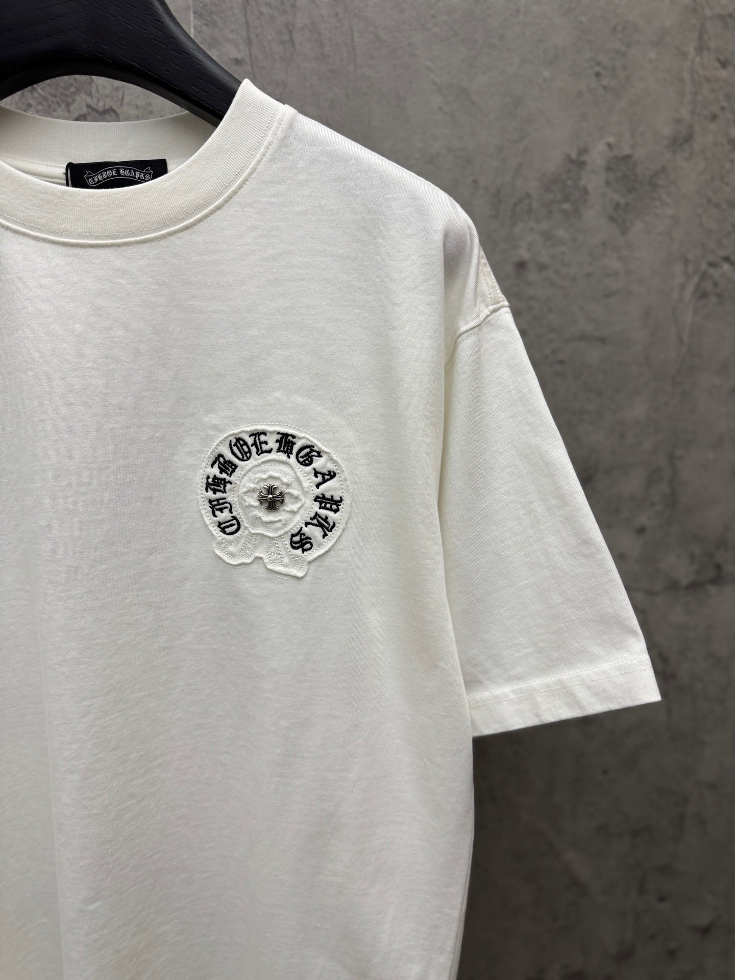 White short-sleeve T-shirt with small circular embroidered logo on chest