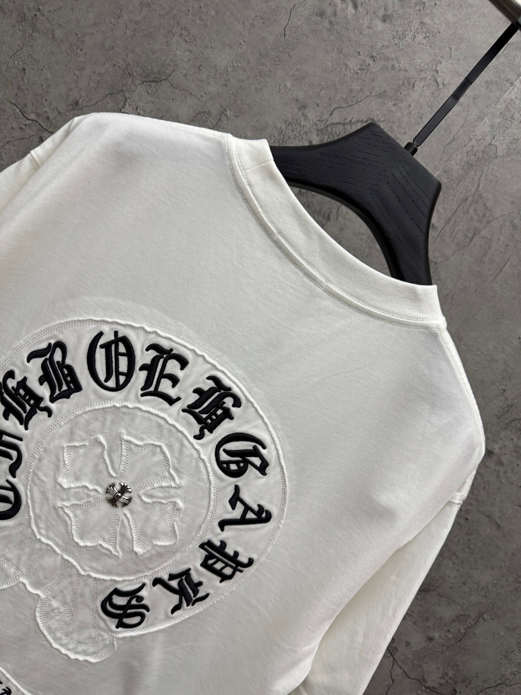 White T-shirt with close-up embroidered circular patch logo on the sleeve chest area