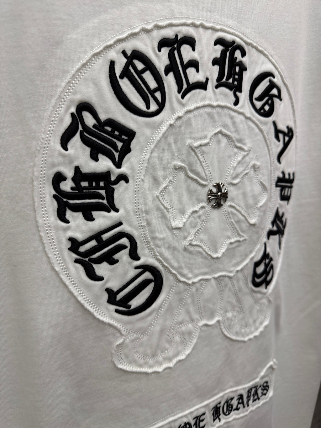 Close-up embroidered circular back logo patch on white T-shirt with center emblem
