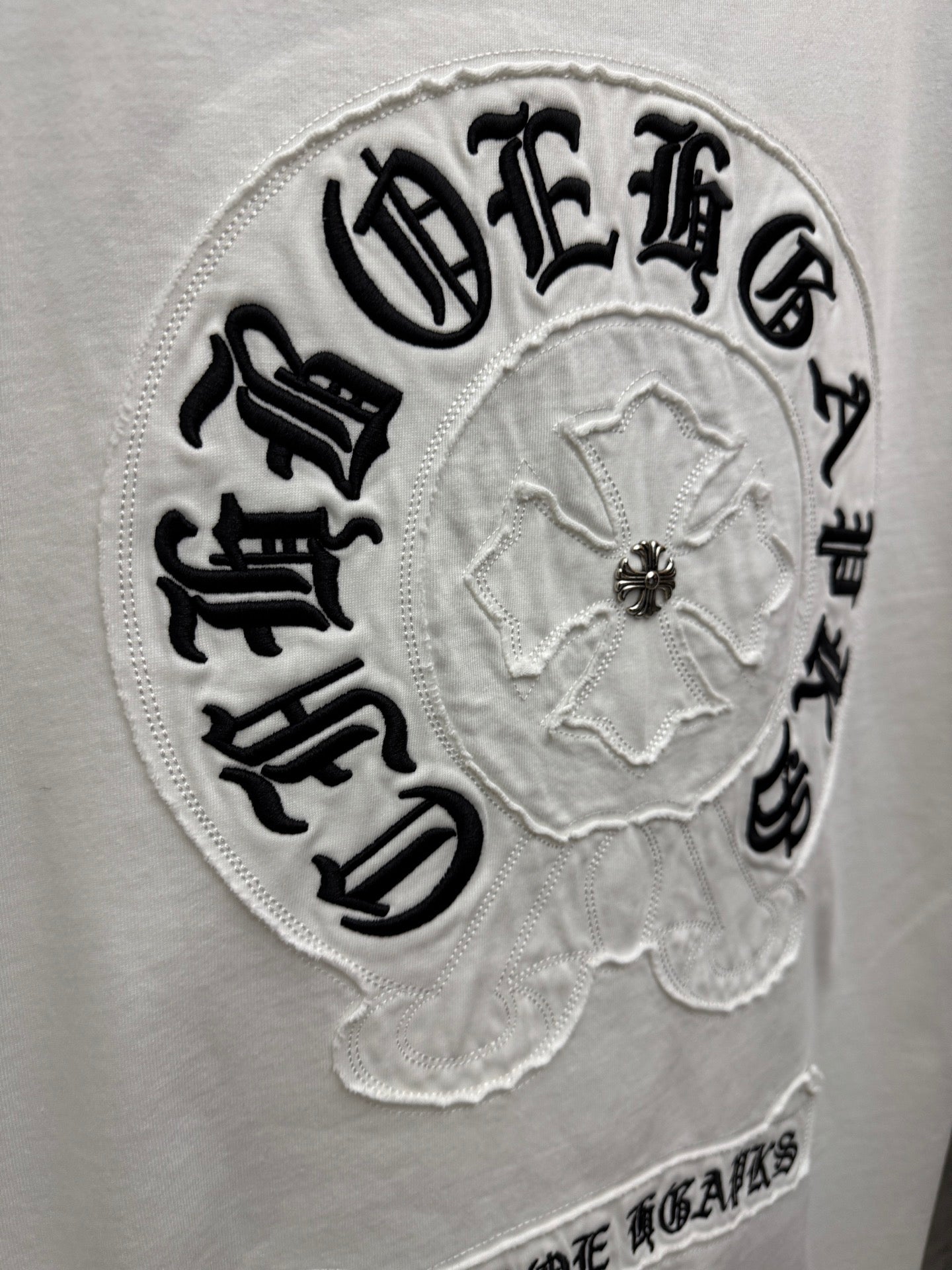 Close-up embroidered circular back logo patch on white T-shirt with center emblem