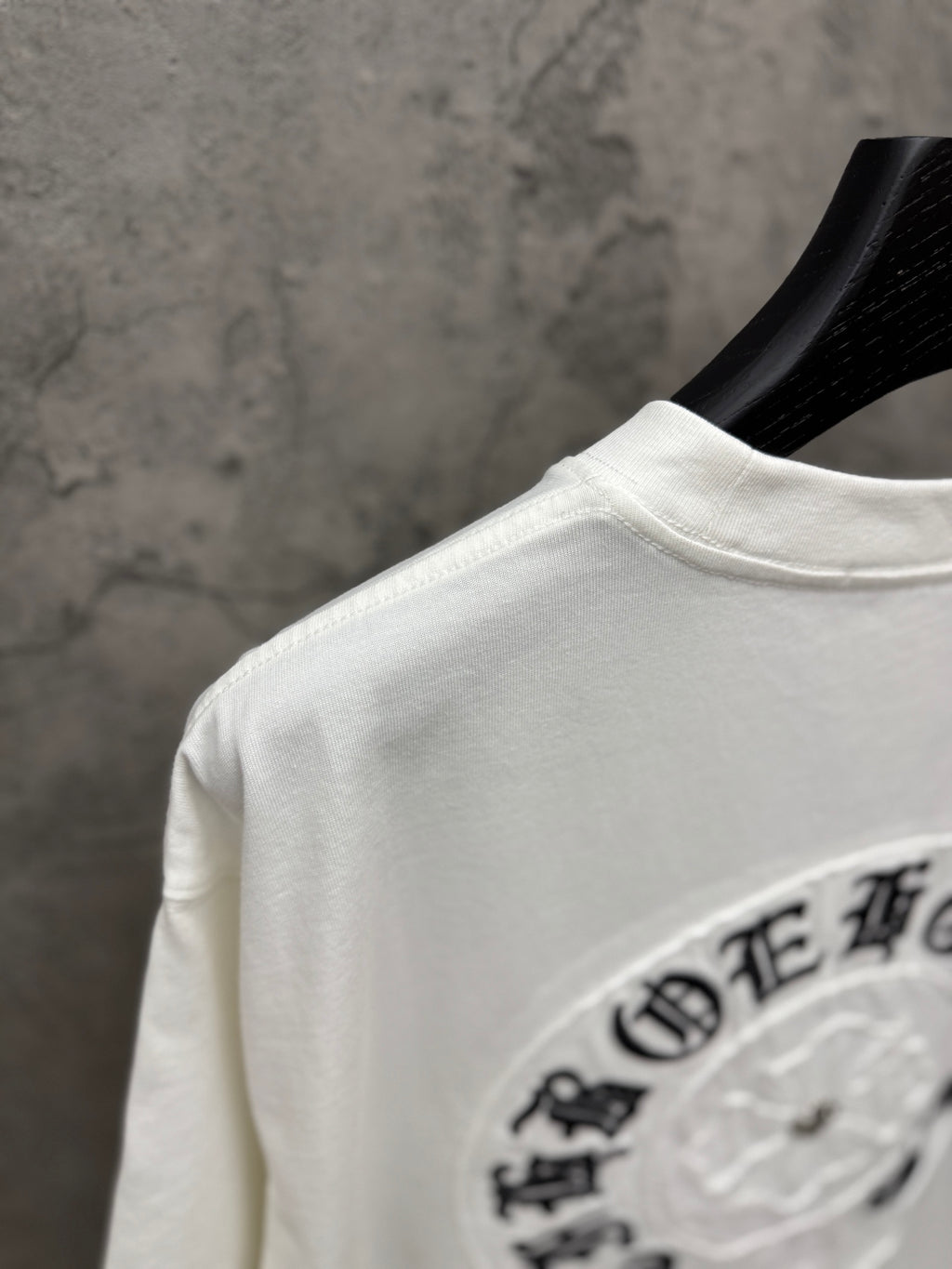 White short-sleeve T-shirt back shoulder view with partial circular logo embroidery