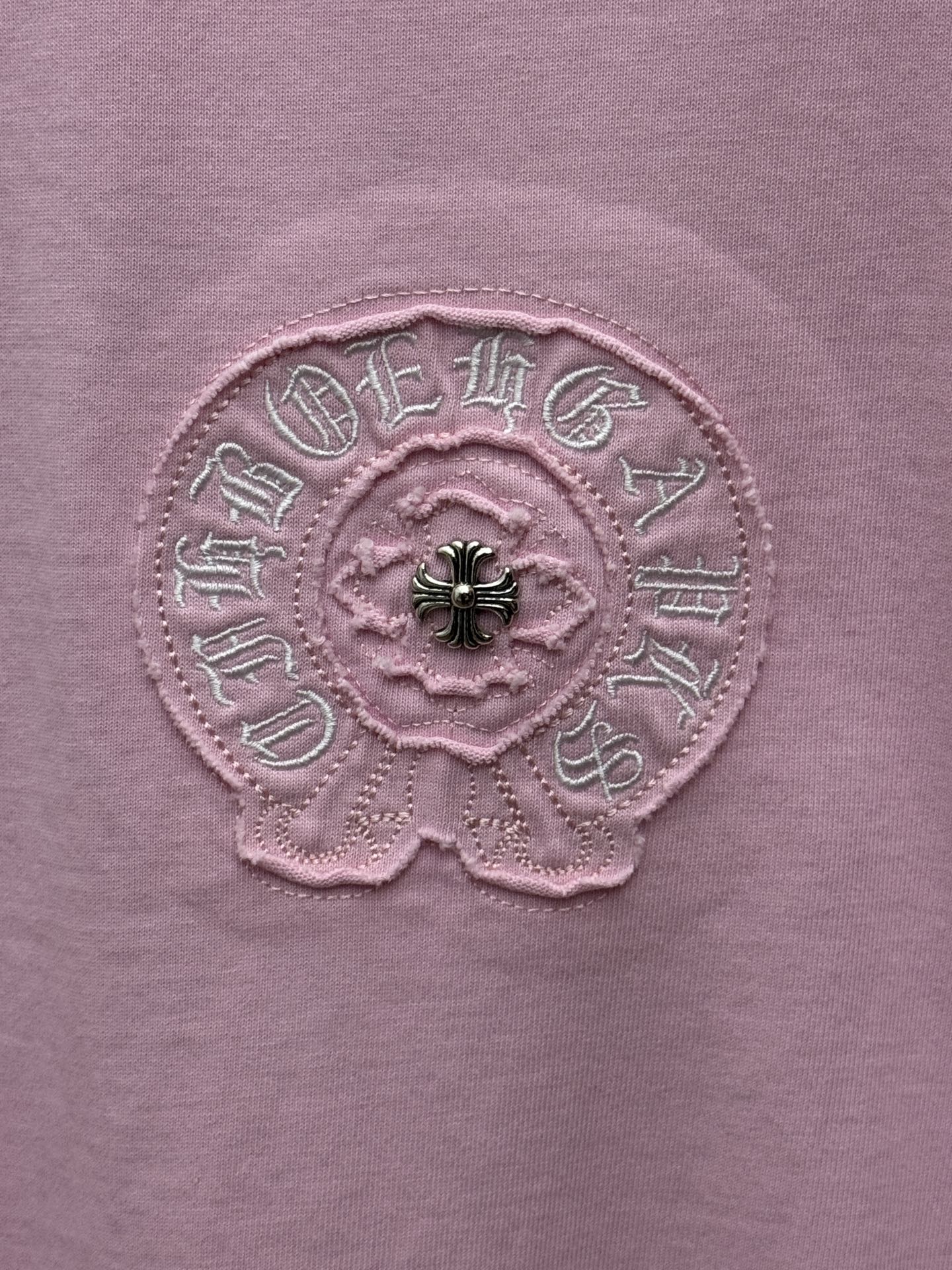 Pink short-sleeve T-shirt close-up of embroidered flower emblem with black bead