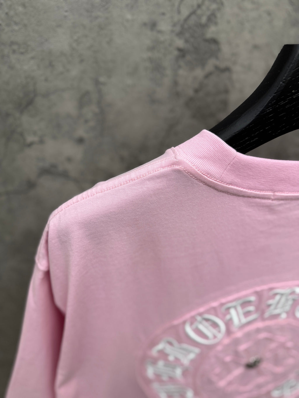 Pink T-shirt back partial view with embroidered emblem near hem