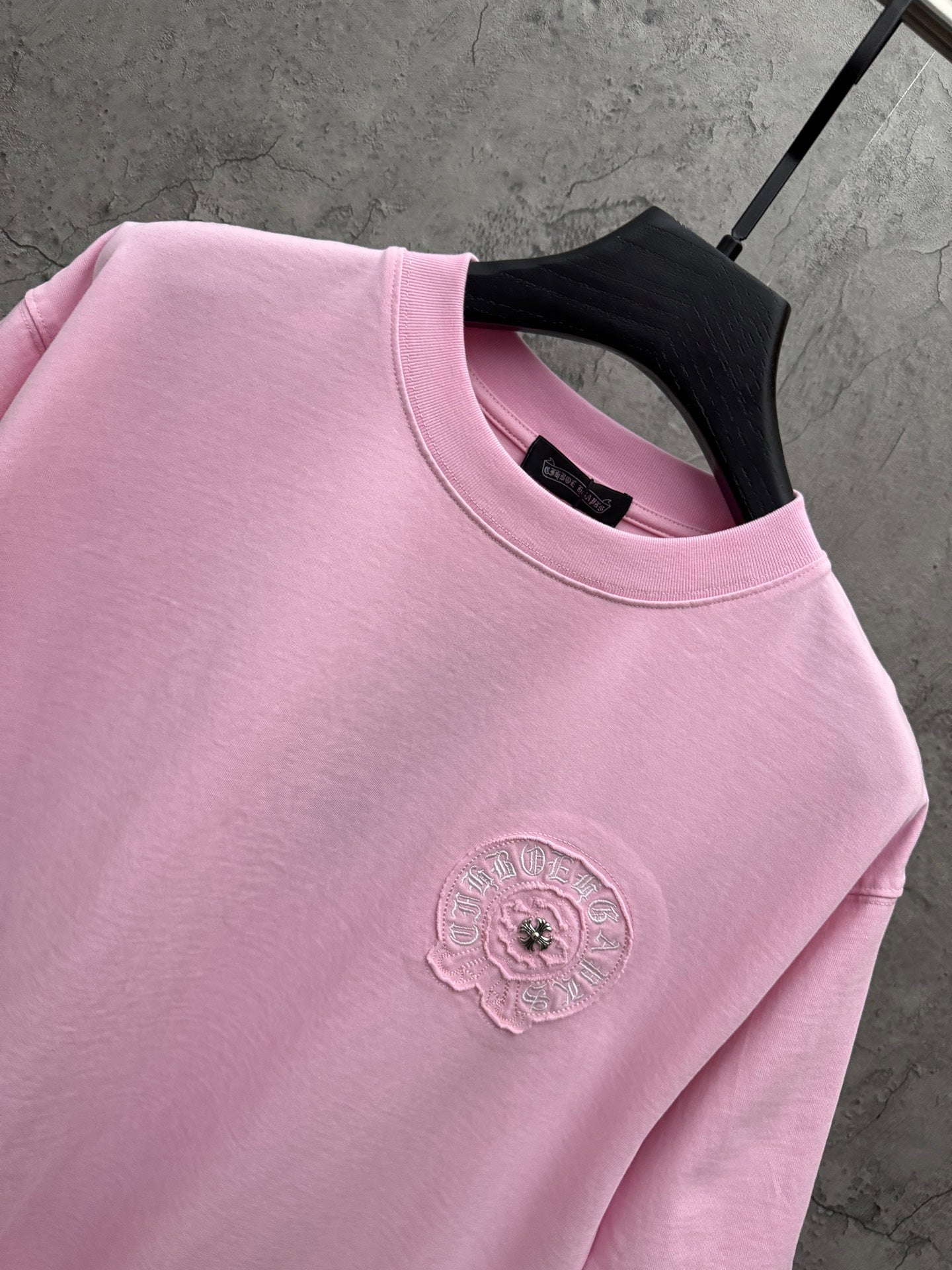 Pink T-shirt close-up of ribbed crew neck and left-chest embroidered emblem