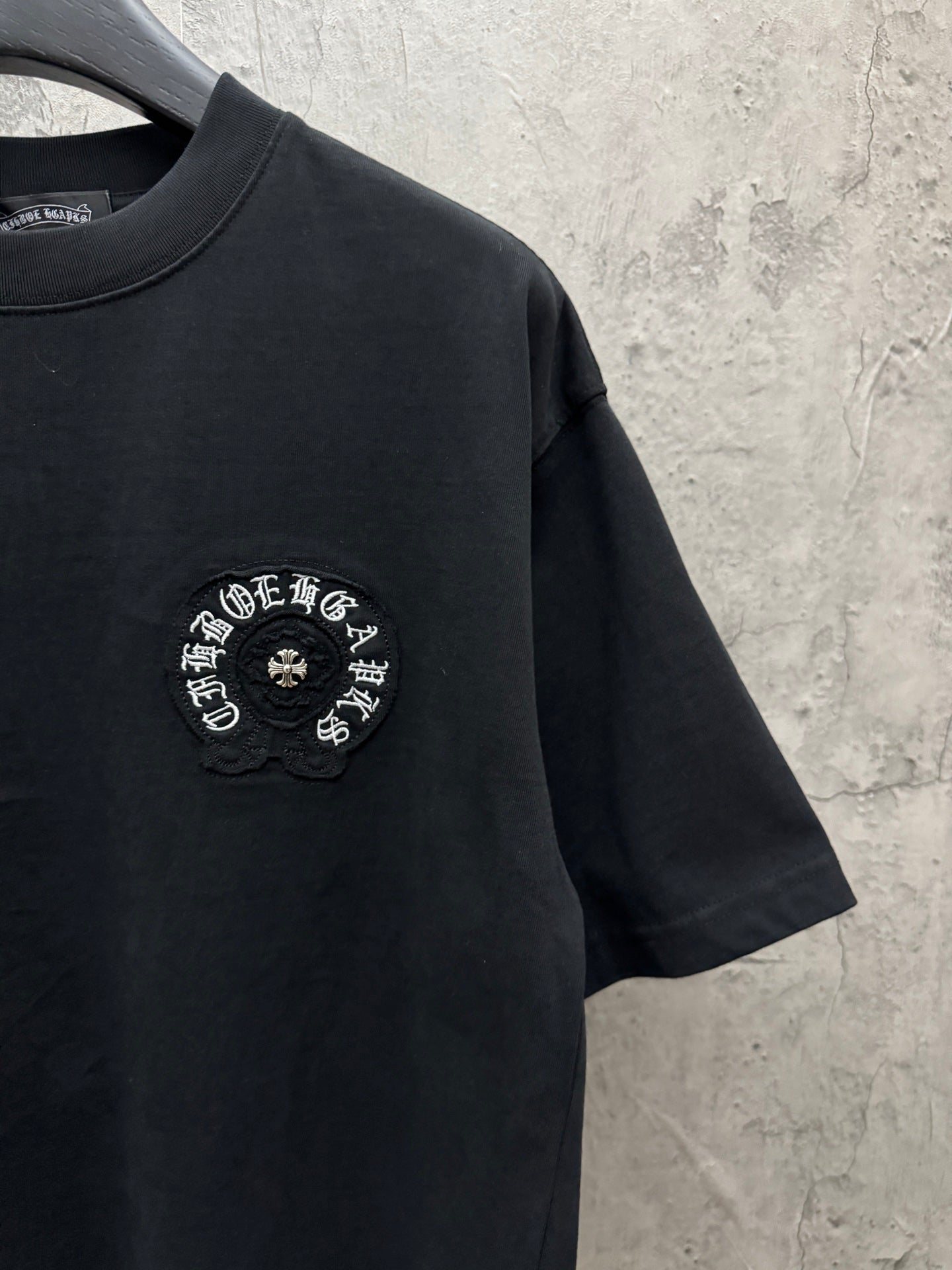 Black short-sleeve crewneck T-shirt with small circular chest logo