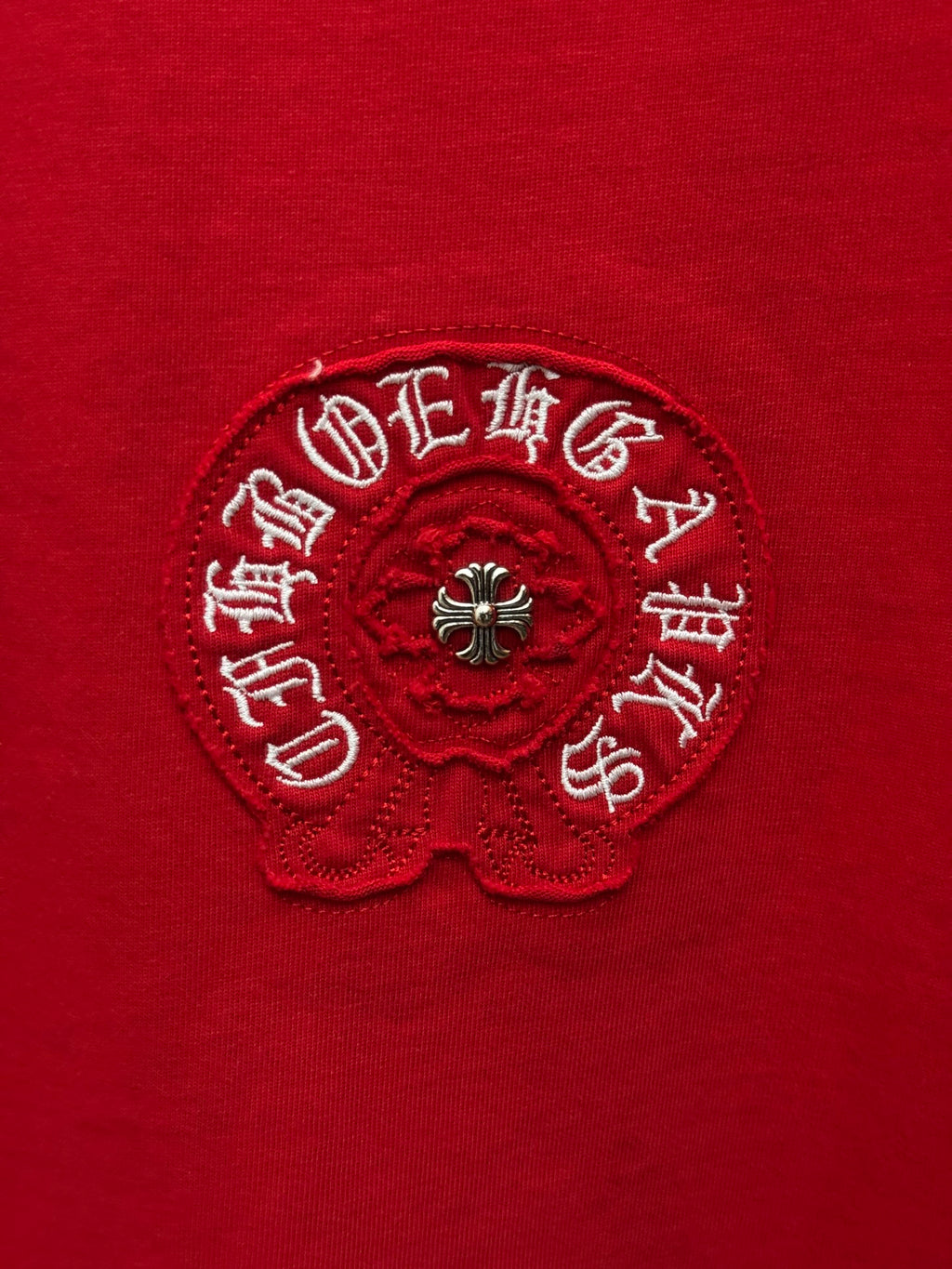 Red T-shirt with circular logo embroidery, close-up on fabric