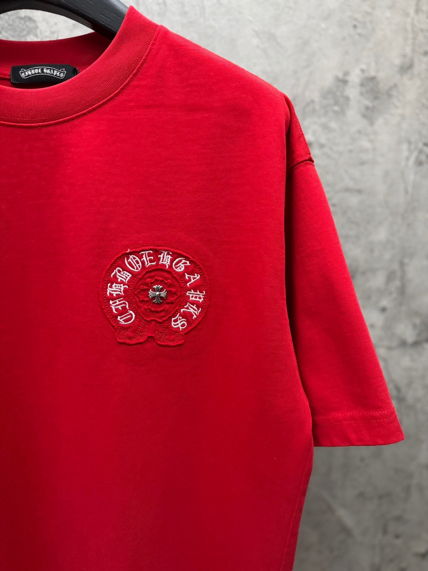 Red crewneck T-shirt with small chest embroidered crest and visible hem