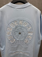 Light blue short-sleeve T-shirt close-up of large embroidered back crest and bottom label
