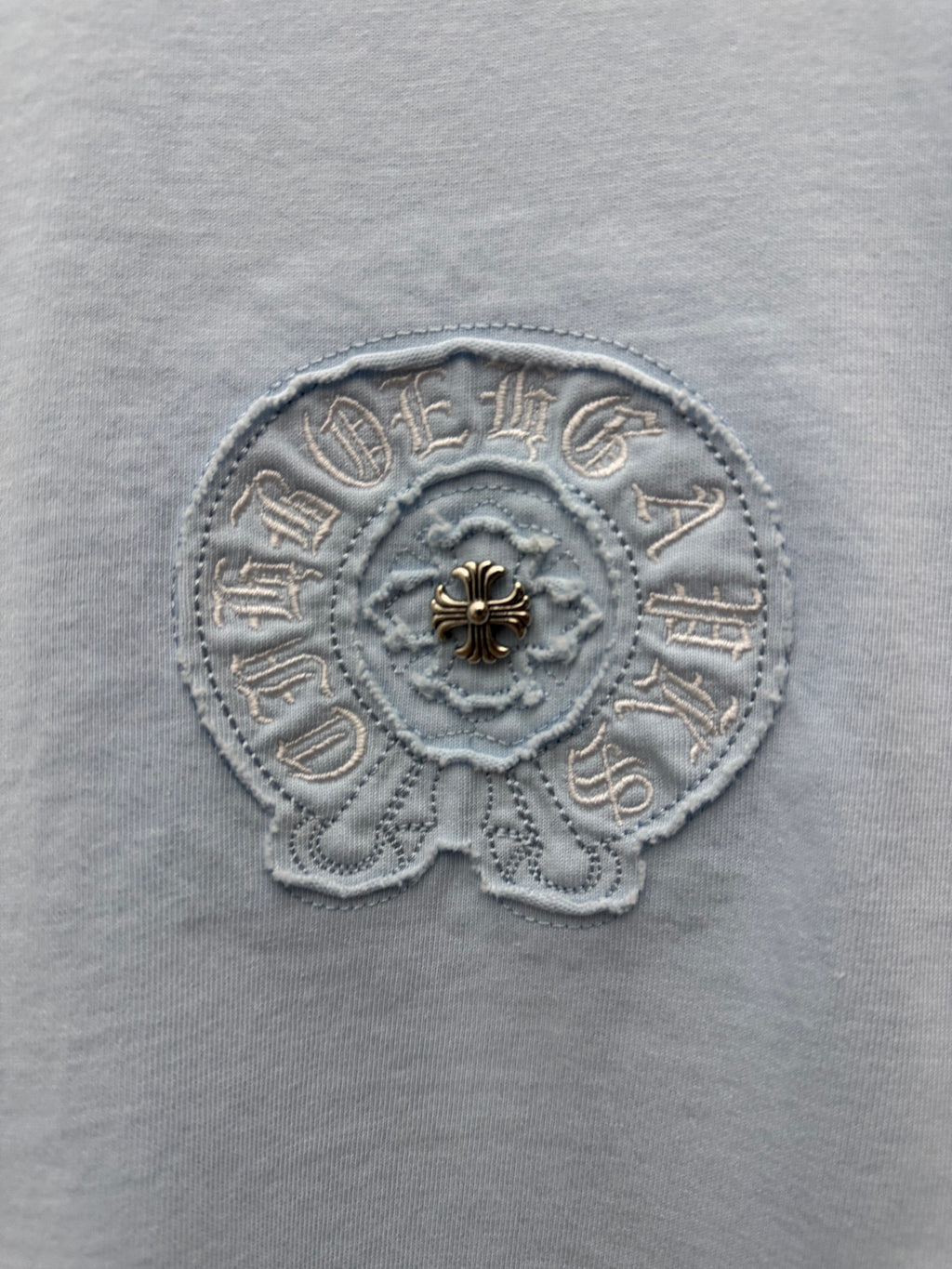 Light blue T-shirt close-up of circular embroidered chest emblem