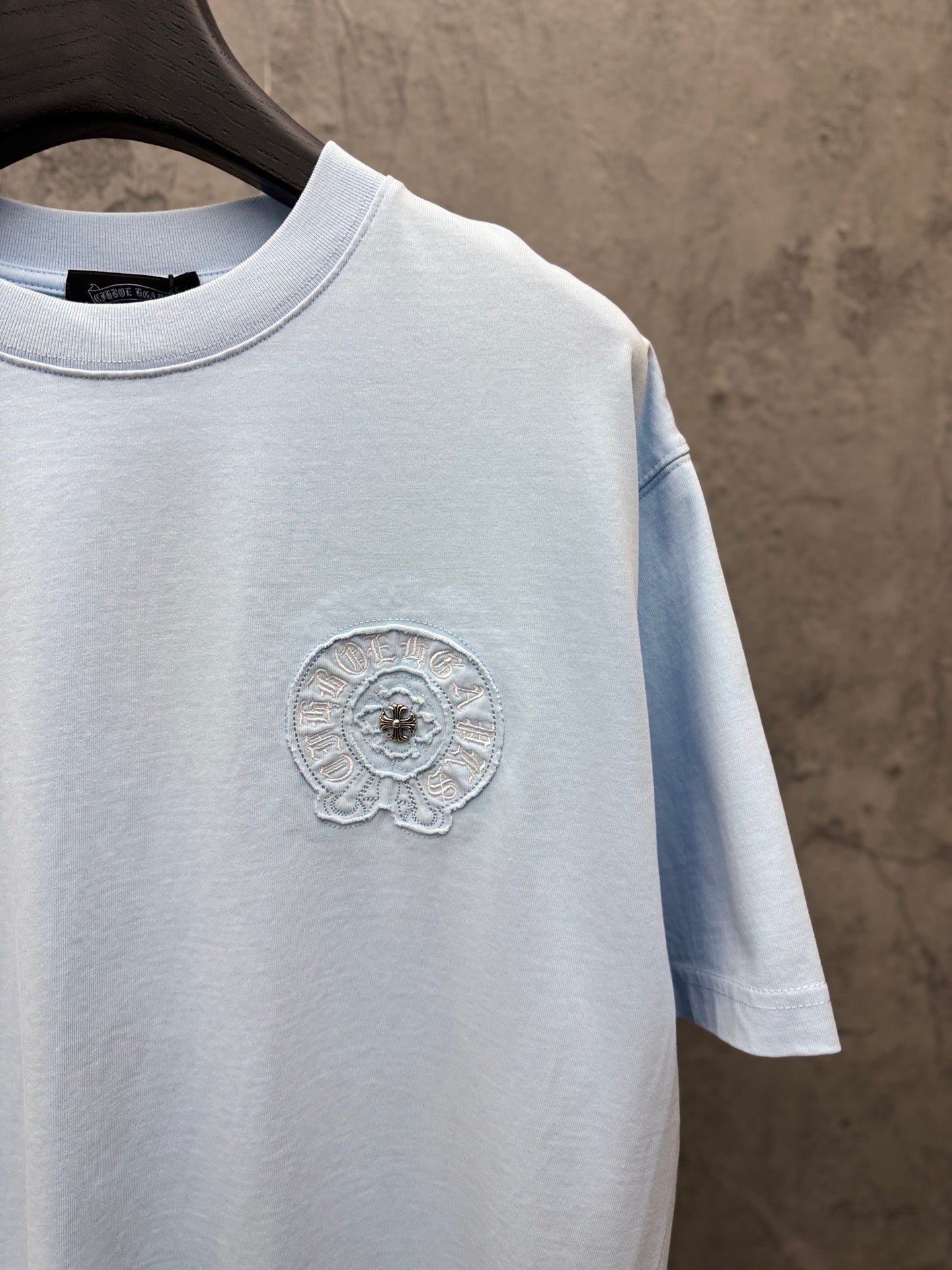 Light blue crewneck short-sleeve T-shirt with small round embroidered chest emblem