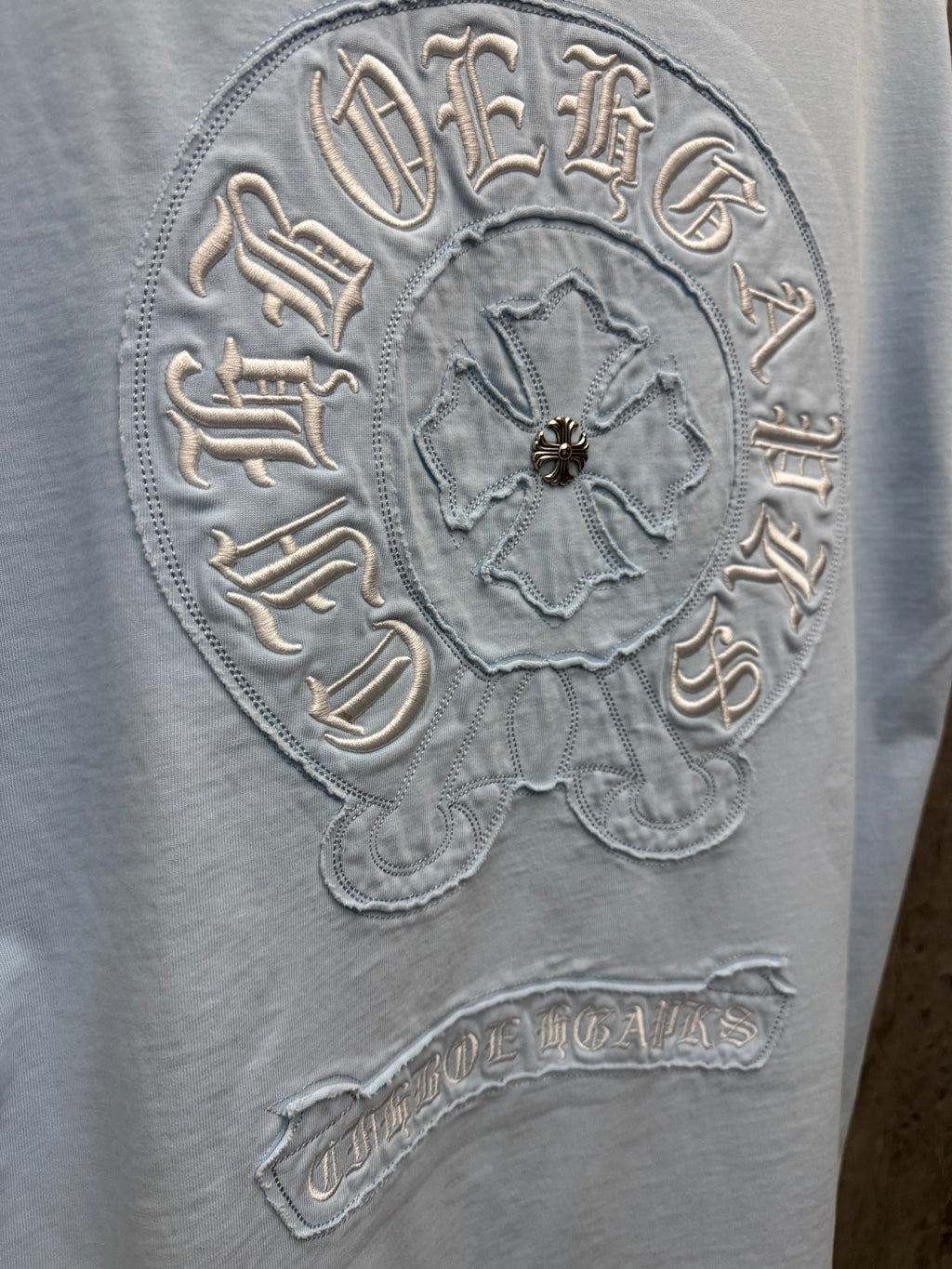 Light blue crewneck T-shirt close-up of embroidered back crest badge