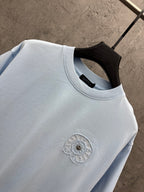 Light blue crewneck T-shirt with embroidered chest detail near neckline