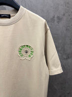 Light cream short-sleeve T-shirt with small green embroidered chest emblem
