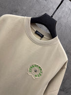 Cream crewneck T-shirt collar with small green embroidered crest patch