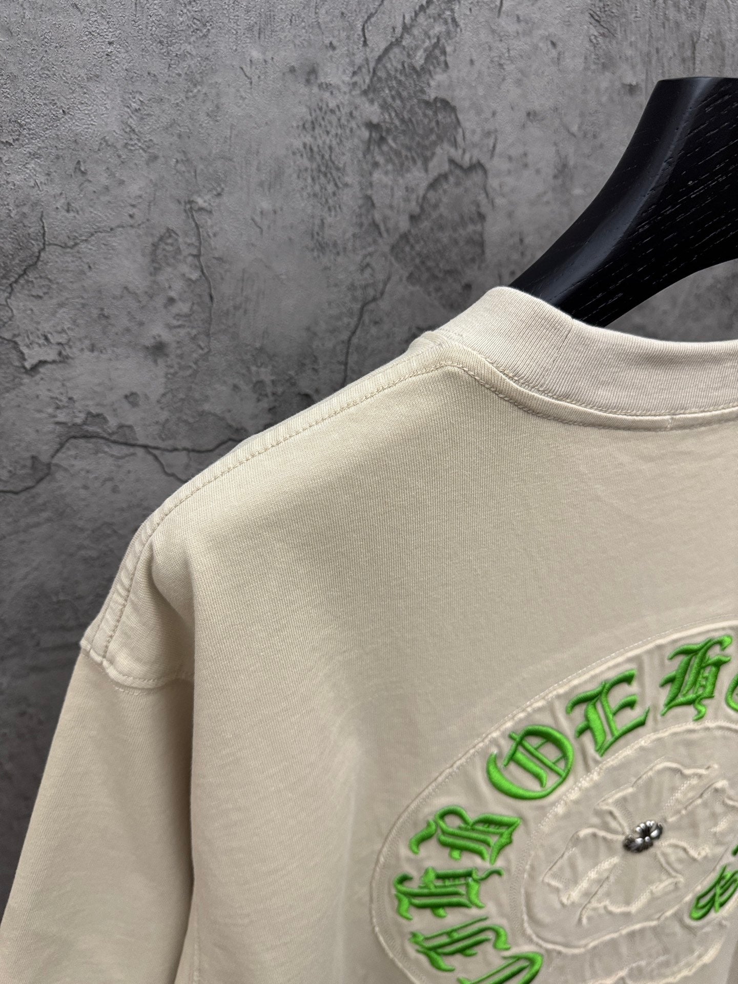 Light cream T-shirt sleeve and side back with partial green embroidered crest