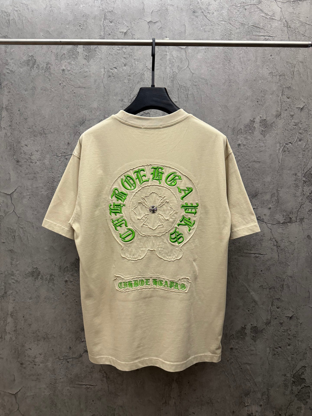 Cream T-shirt with large green embroidered back crest graphic and text