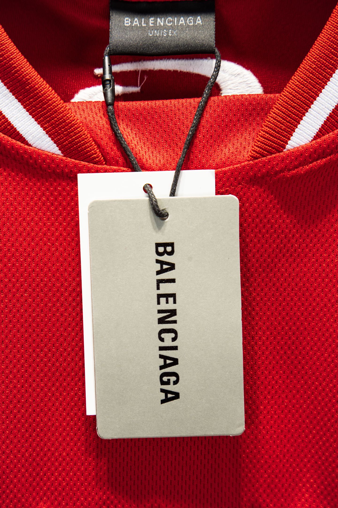 Red Balenciaga jersey with white neck label reading BALENCIAGA, on black clips