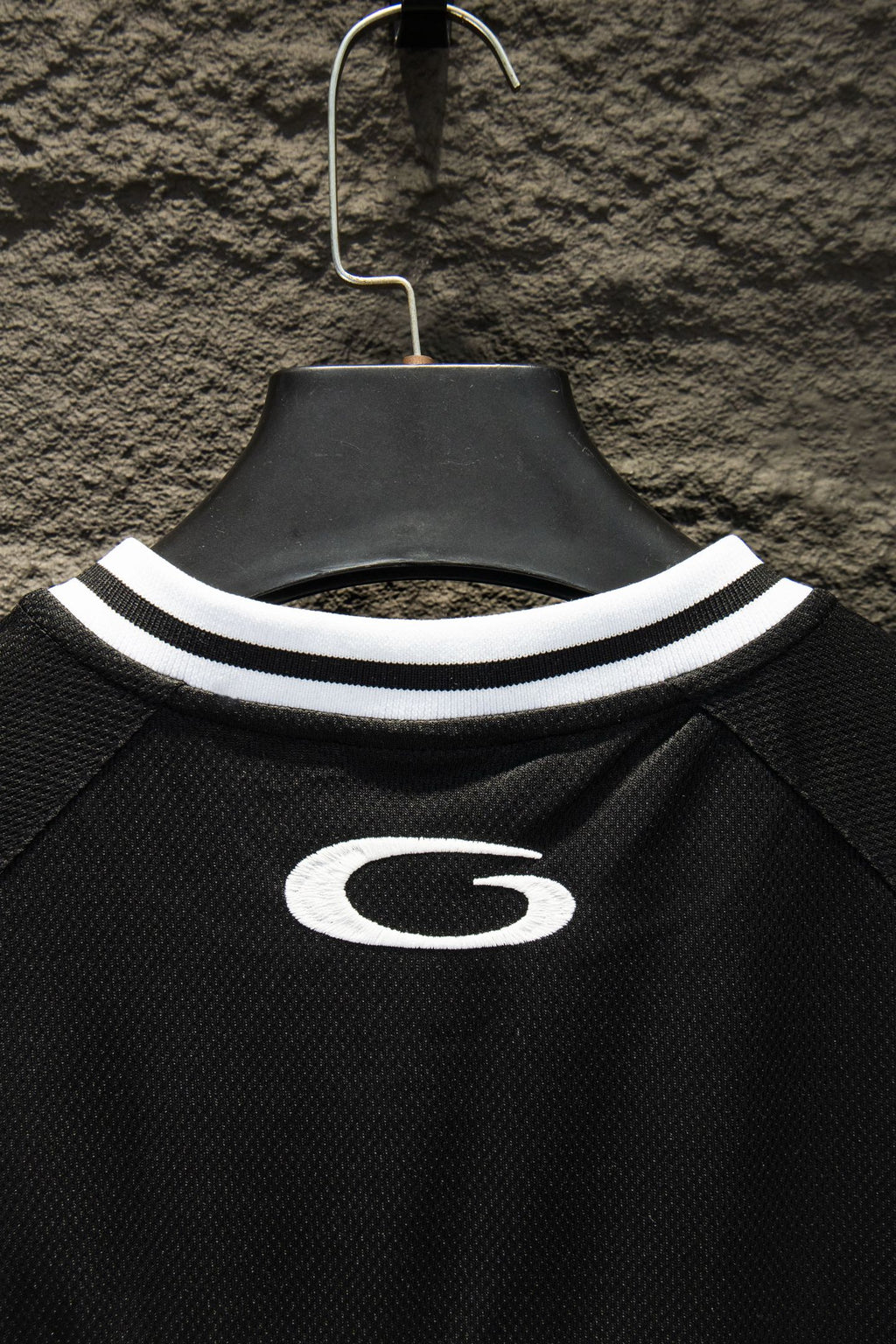 Black short-sleeve jersey neckline with white striped collar and oval G emblem