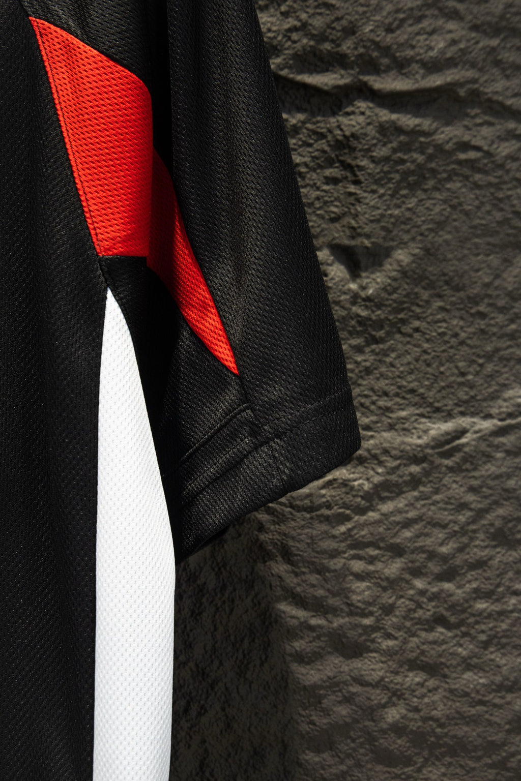 Black jersey side with red shoulder panel and long white stripe