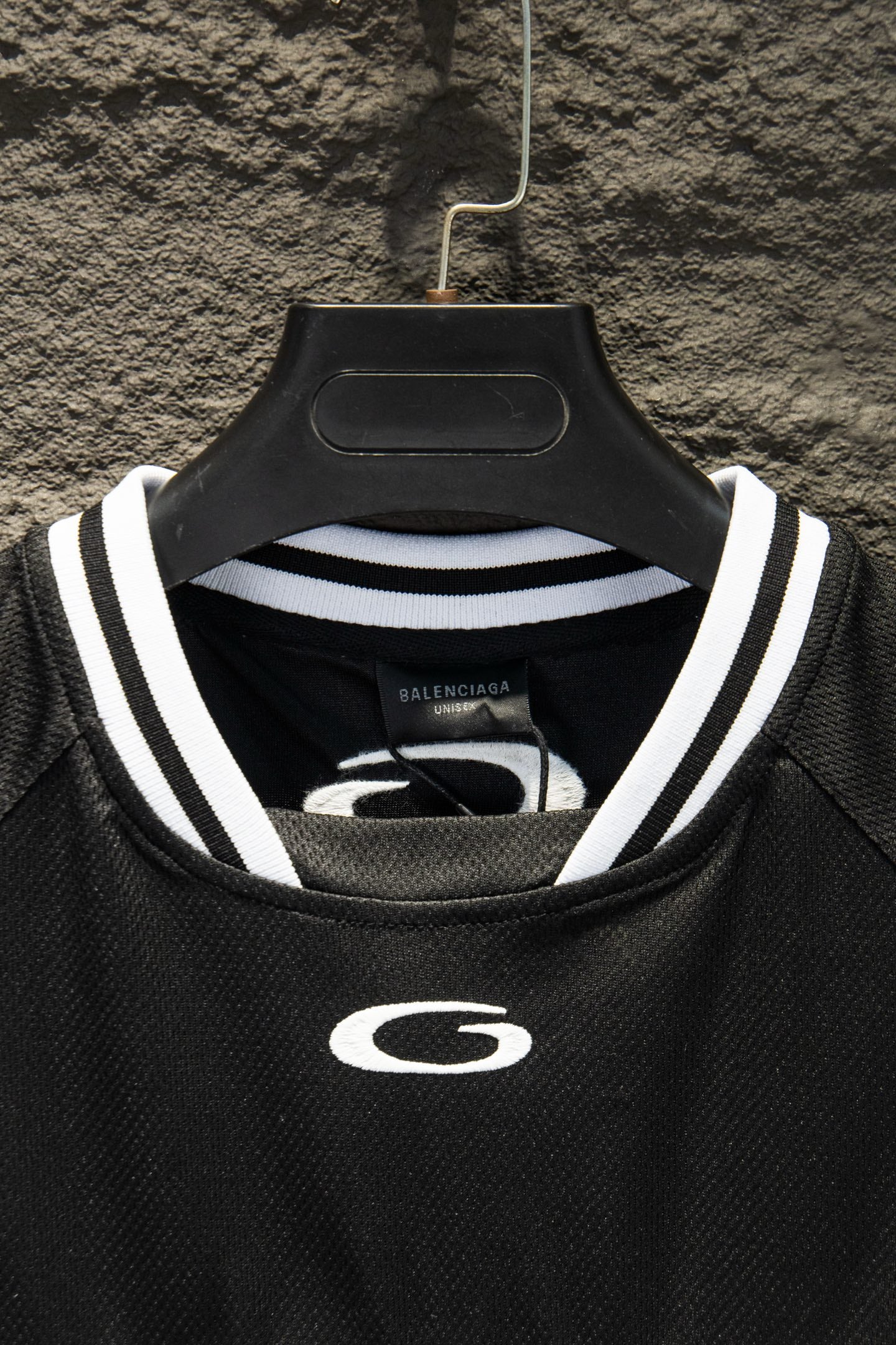 Black collar of short-sleeve jersey with white-and-gray striped trim and G emblem