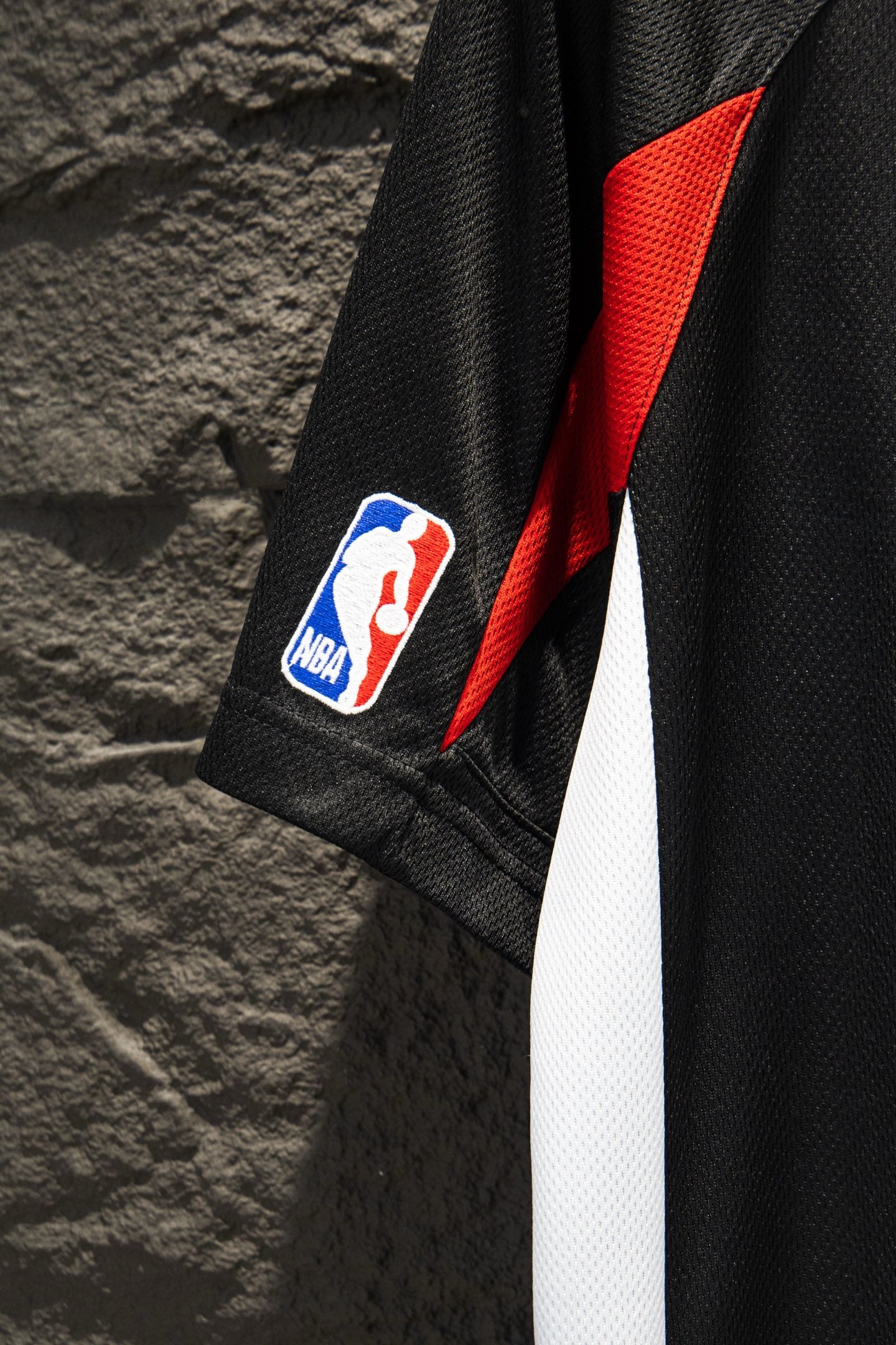 Black jersey sleeve with red angular panel and NBA patch logo