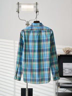 Blue-green plaid button-up shirt back view with pointed collar on hanger