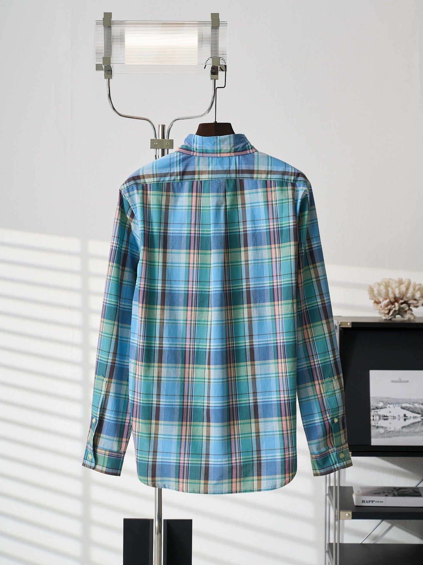 Blue-green plaid button-up shirt back view with pointed collar on hanger