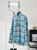 Blue-green plaid button-up shirt front view with button placket on hanger