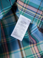 Turquoise plaid shirt with white care label tag near collar