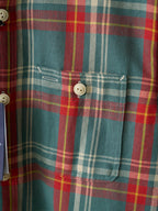 Teal plaid button-up shirt with chest pocket and white buttons, close-up