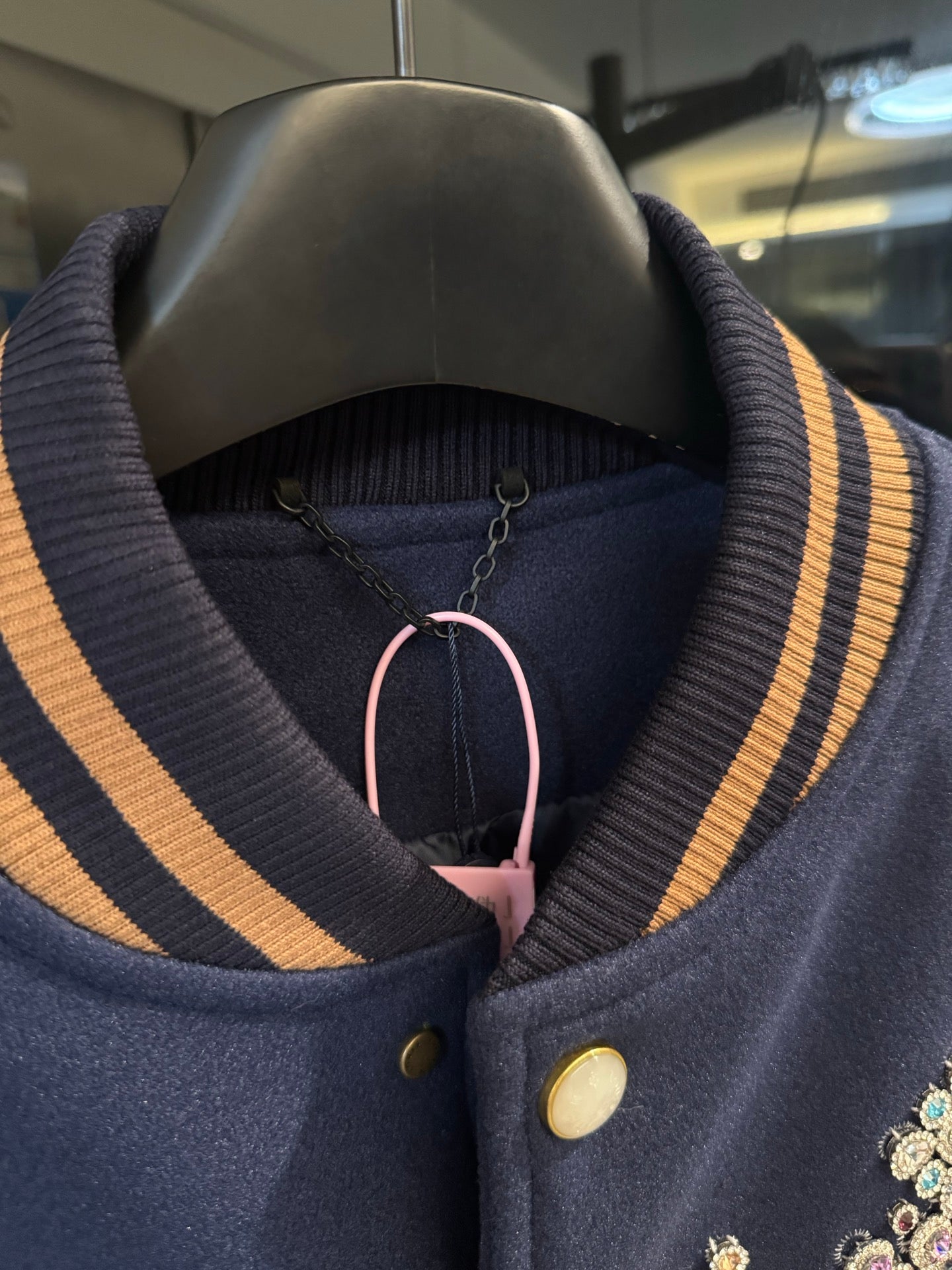 Long varsity jacket collar close-up with striped ribbing and snap button placket