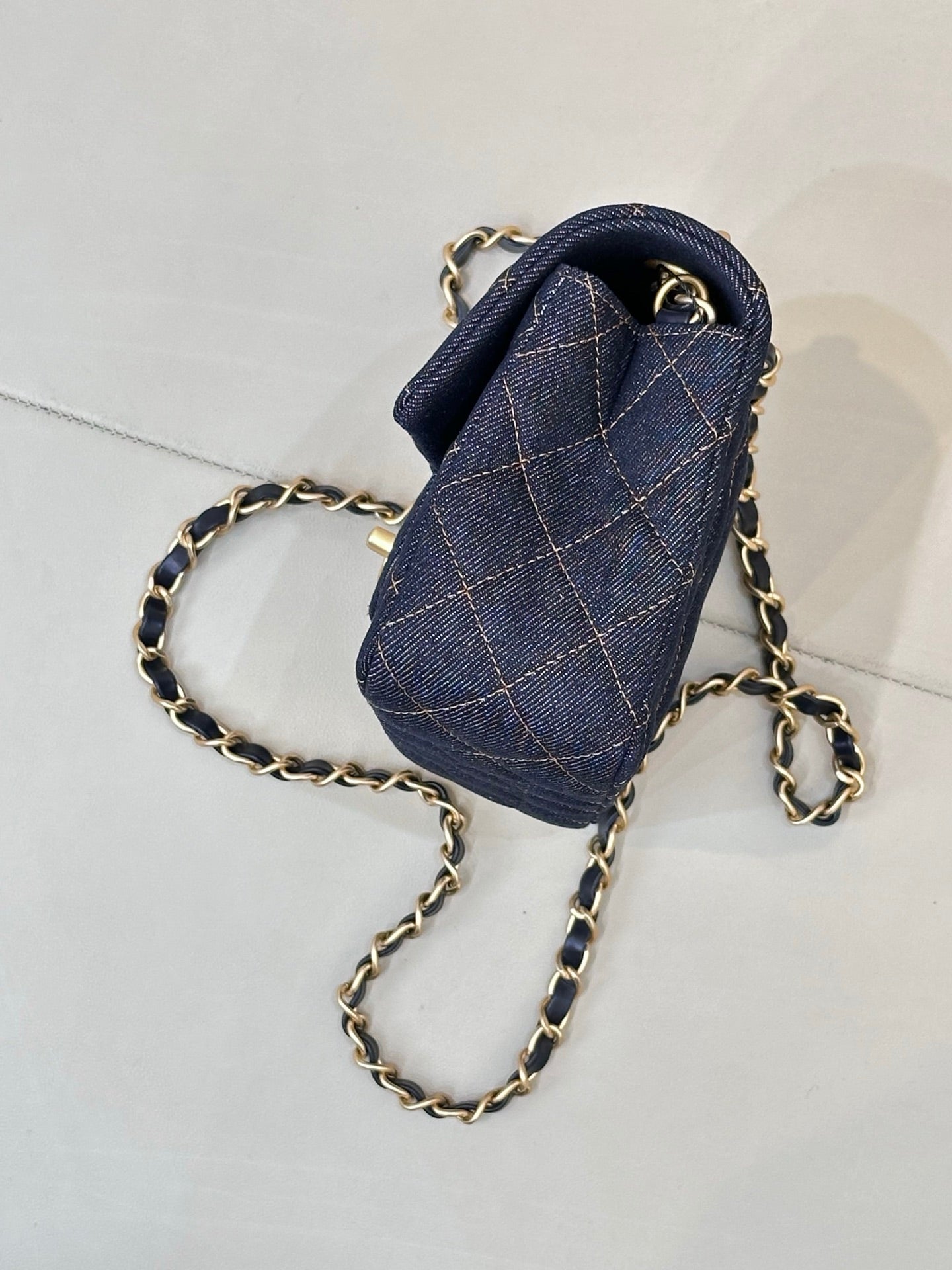 Chanel small denim flap bag with quilted pattern and gold chain strap.