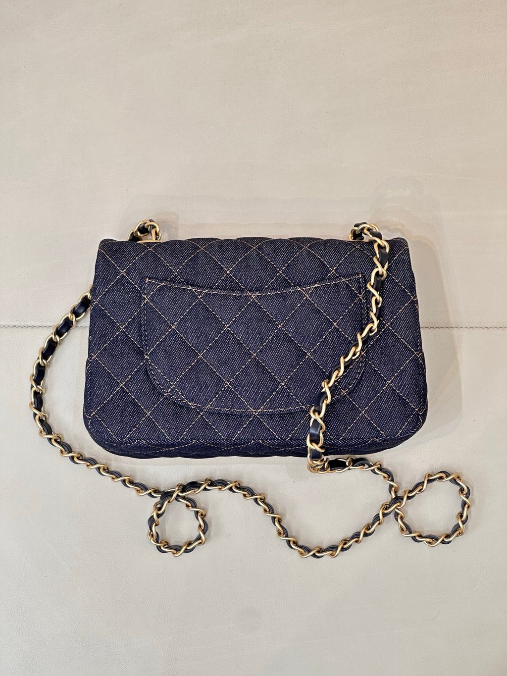 Chanel quilted denim flap crossbody bag with gold CC logo and chain strap.