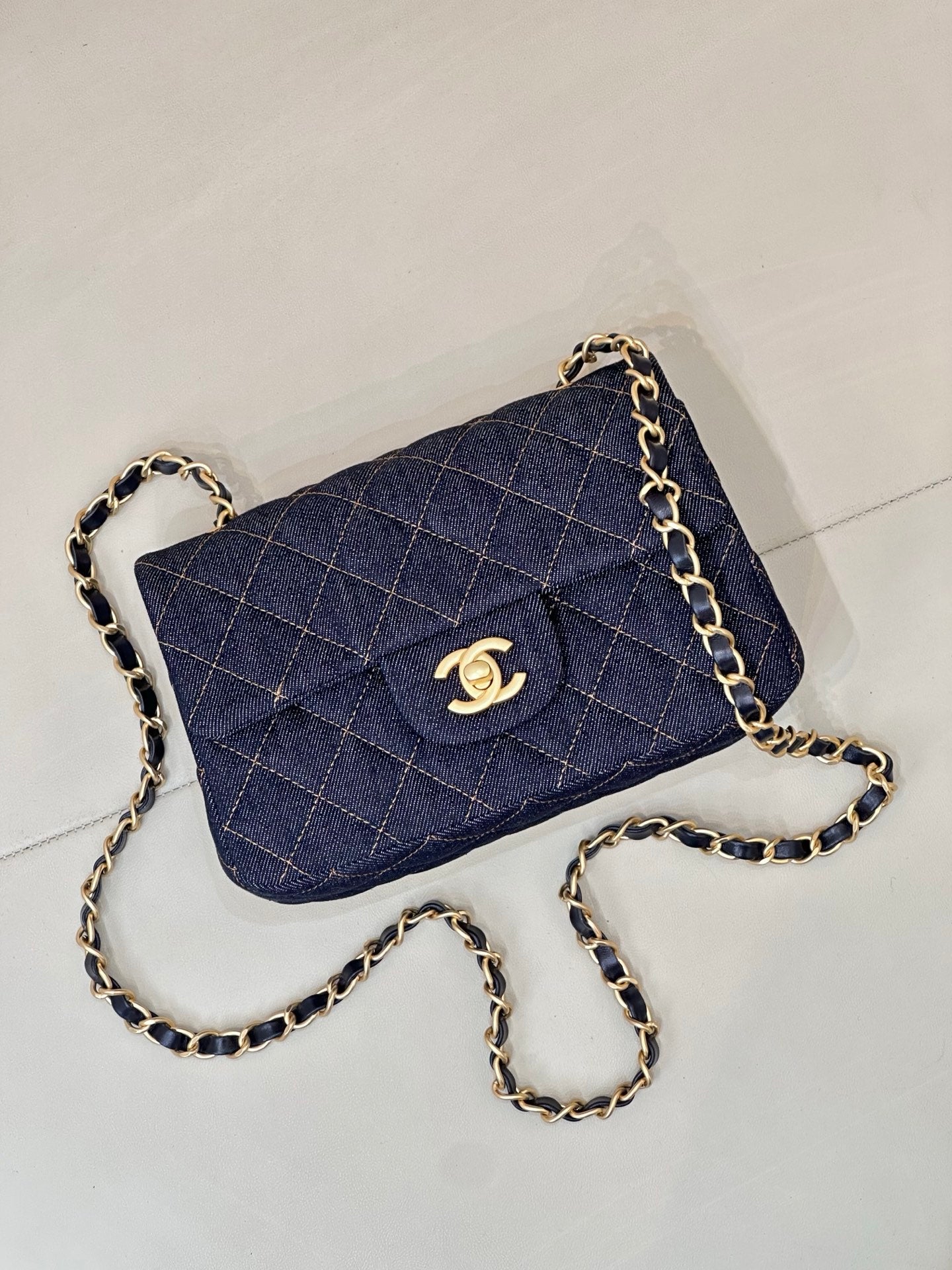 Chanel quilted denim crossbody bag with gold CC logo and curb chain strap.