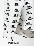 White shirt cuff and side placket detail with black logo pattern and buttons.