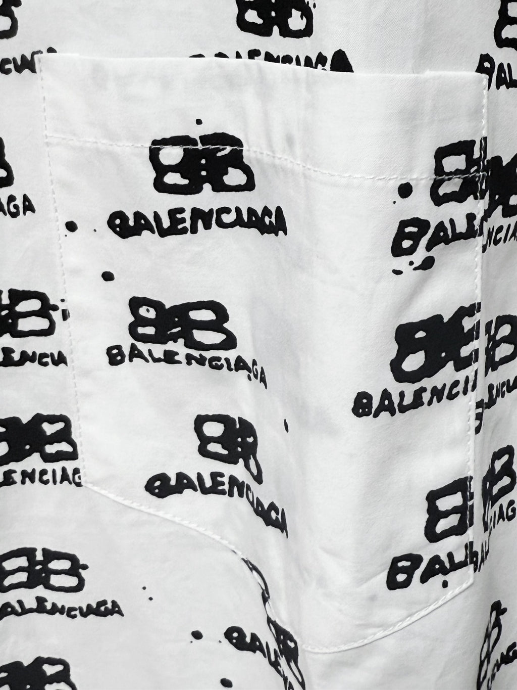 Close-up of white fabric with black logo icons and text pattern.