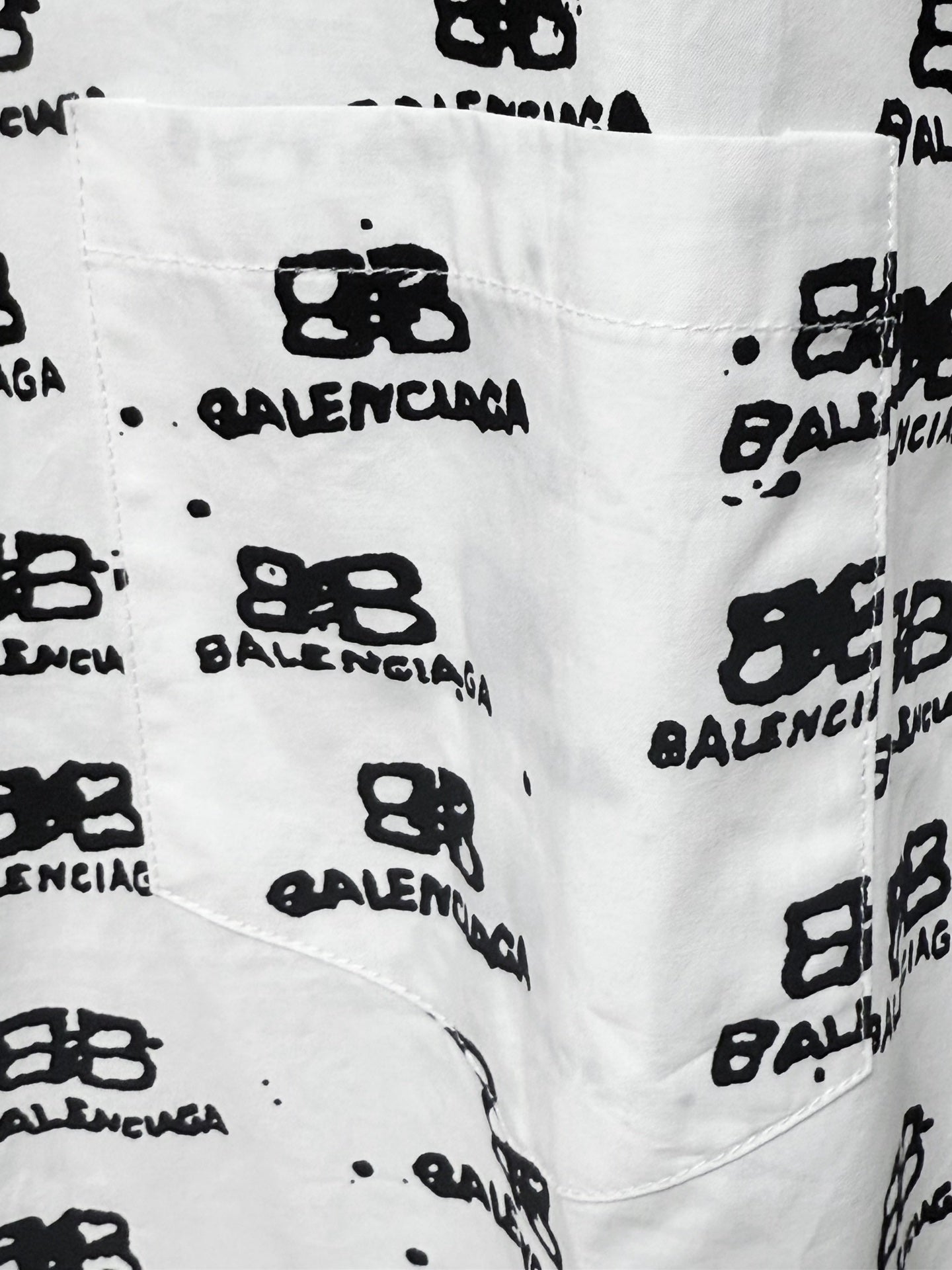 Close-up of white fabric with black logo icons and text pattern.